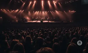 A band performs on a stage to a large audience in a concert hall.