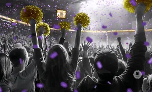 Crowd cheering at a concert with purple confetti and gold pom-poms.