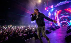 Rapper performing on stage for a large crowd holding up their phones.
