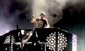 DJ performing on stage with a skull t-shirt, headphones, and dramatic lighting.