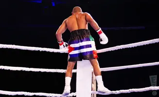 Boxer in shorts with flag design stands in a boxing ring.