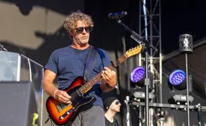 Guitarist plays a sunburst Fender Telecaster guitar on stage under bright lights.