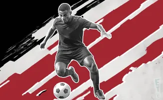 A soccer player dribbles a ball against a red and white striped background.