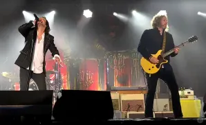 A singer on stage with a microphone and a guitarist playing a yellow guitar.