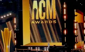 ACM Awards stage with large gold lettering and a spotlighted performer.