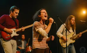 A band performs on stage with a singer, guitarist, and bassist under stage lights.