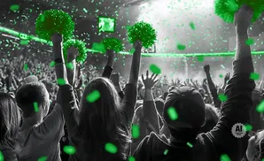 Crowd cheering with green pom-poms and confetti.