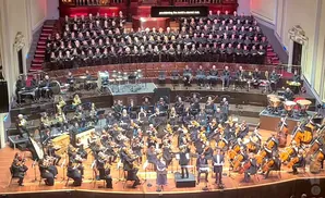An orchestra and choir perform on a stage.