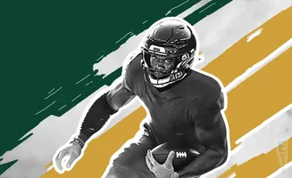 A football player in a dark jersey and helmet runs with a football, against a green and gold background.
