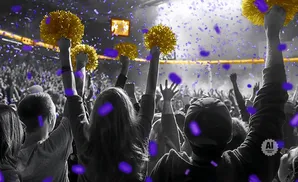 People in a crowd cheer with pom-poms as purple confetti falls around them.