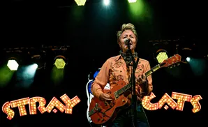 Guitarist plays on stage under bright lights with 