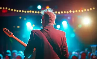 A guitarist in a red suit performs on stage with bright blue and yellow lights.