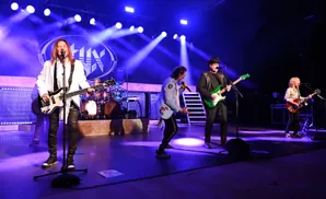 A band performs on stage with blue lights and fog.