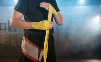 Boxer wrapping hands in yellow hand wraps.