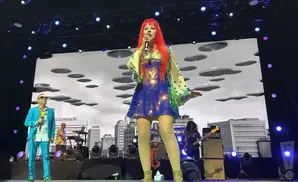 A singer with bright red hair performs on stage in a sequined blue dress.