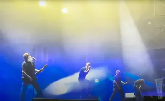 Band performs on stage under bright yellow and blue lights.