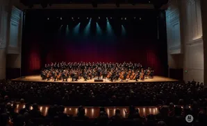 An orchestra and choir perform on a stage in a concert hall to a seated audience.
