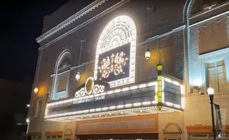 Exterior of Pittsburgh Ballet Theatre at night, illuminated by marquee lights and building spotlights.