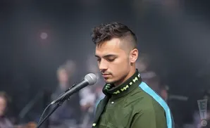 a close up picture of indie artistis puma blue performing on stage in front of a microphone