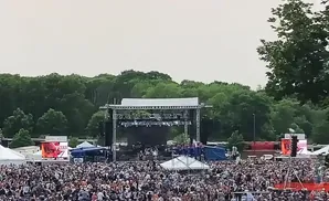 A crowded outdoor concert with a large stage and a dense audience.