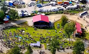 An aerial view of an outdoor concert with a large crowd gathered on a grassy field.