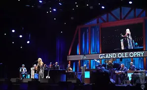 Singer on stage with a band at the Grand Ole Opry.
