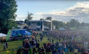 An outdoor concert with a large crowd gathered in front of a stage.