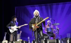 Marty Stuart and His Superlatives perform on stage with Marty playing guitar and singing.