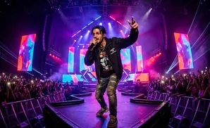Rapper performing on stage with a crowd in the background, holding a microphone and pointing.