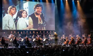Star Wars orchestra performance with iconic characters projected on screen.