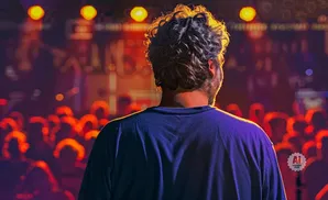 Man with curly hair seen from behind, facing a crowd at a concert.