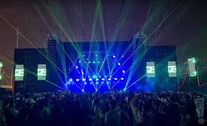 A crowd enjoys a concert with a stage bathed in blue and green lasers.