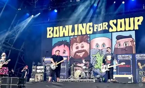 Bowling for Soup band performing on stage with cartoon band members behind them.