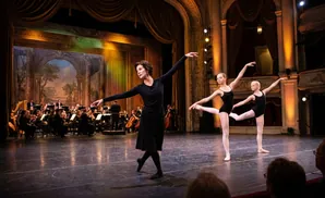 Ballet dancers in colorful costumes perform on a stage with a candy-themed backdrop.