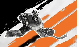 A hockey goalie in full gear crouches low, ready to make a save.