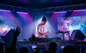 DJ performing on stage with colorful cosmic visuals and lights.