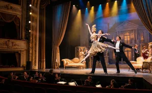 A ballet performance on stage with dancers in costume and an orchestra in the pit.