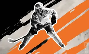 A hockey player in uniform skates forward with a stick.