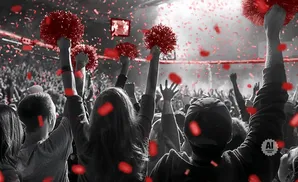 Crowd with red pom-poms and confetti at a concert or sporting event.
