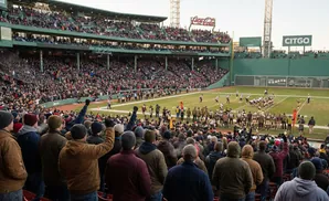 Fans in baseball stadium seats watch an American football game.