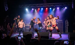 Wrestlers face off on stage with a crowd watching.