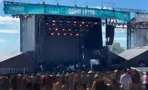A band performs on a large outdoor stage at the Lasso Festival, with a crowd of people in the foreground.