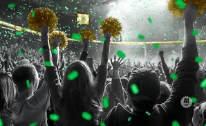 Fans cheer with gold pom-poms and green confetti at a concert.