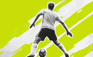 A soccer player in black shorts and white jersey kicks a ball, set against a bright green and white abstract background.