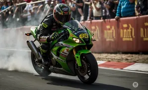 A motorcycle racer in a black and green suit drifts a green motorcycle, kicking up smoke, in front of a crowd.