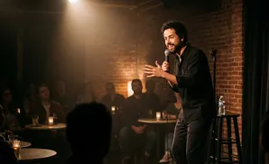 A comedian tells jokes to a dimly lit audience.