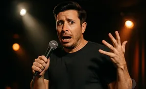 A man holding a microphone with a surprised expression and his hand gesturing.