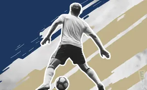 Soccer player in black and white, dribbling a ball, with blue and tan abstract background.