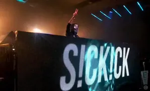 A masked DJ stands behind a large LED screen displaying 