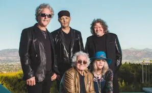 Five people posing for a photo with a landscape in the background.